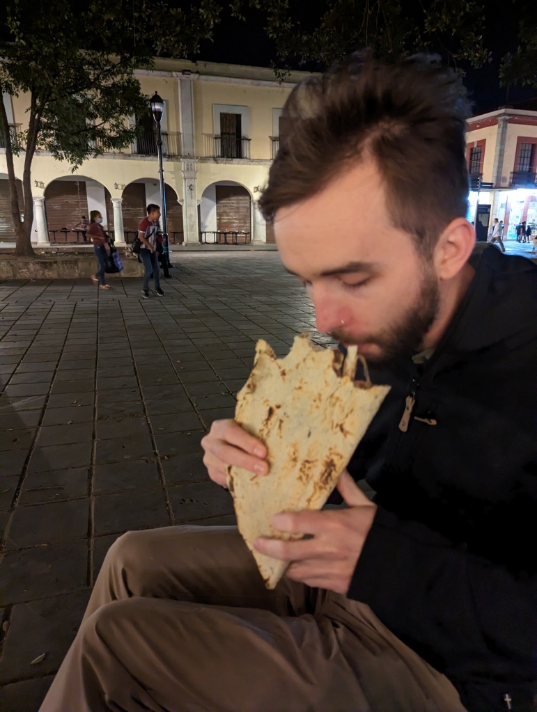 Handsome man eating a tlayuda.